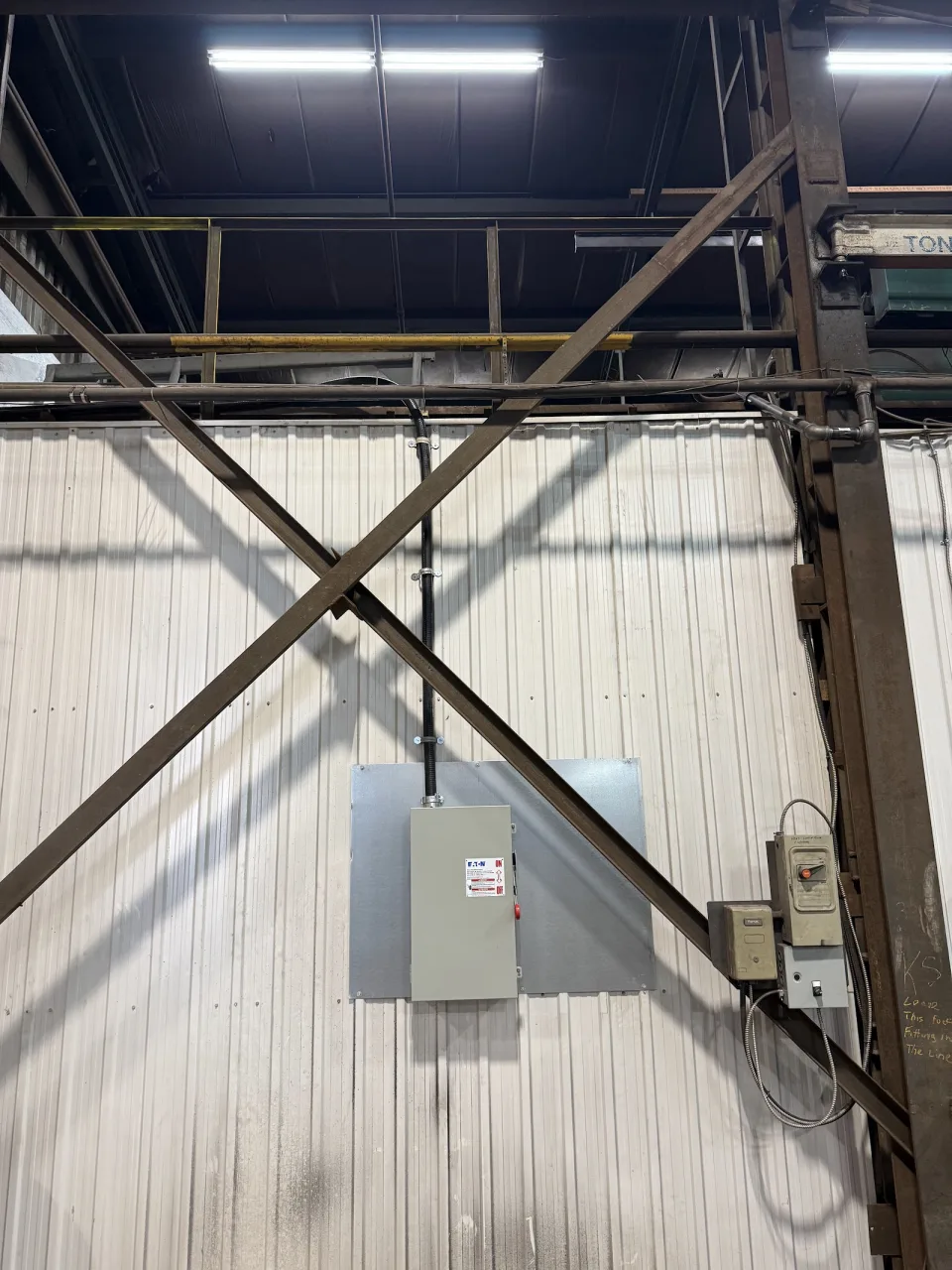Overhead lighting, electrical panel and surface conduit inside a commercial building.