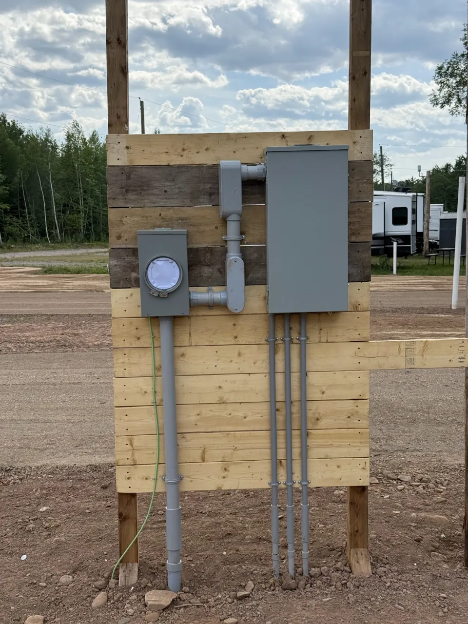 Outdoor electrical panel, meter and conduit mounted on a timber support.