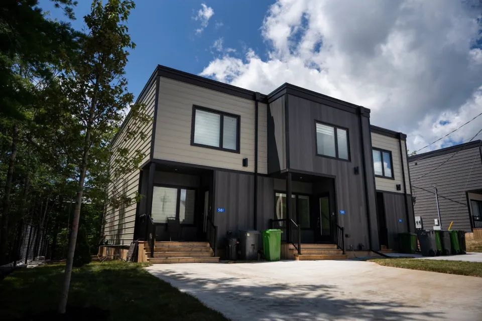 Dark vertical siding and light accent panels around black-framed windows.