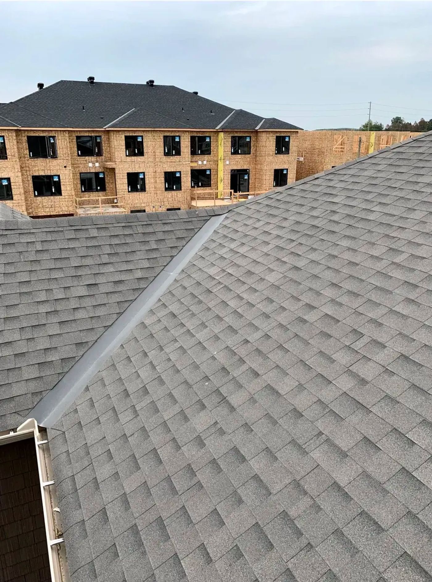 New roof on a home with a multi-unit build under construction behind it